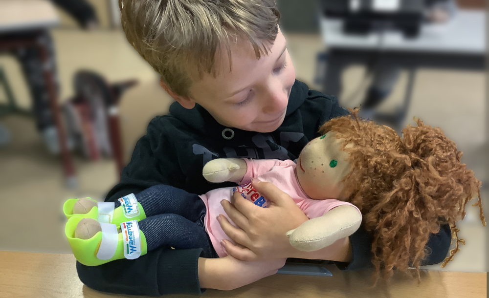 Ein Junge hält eine Handicap Doll in seinem Arm