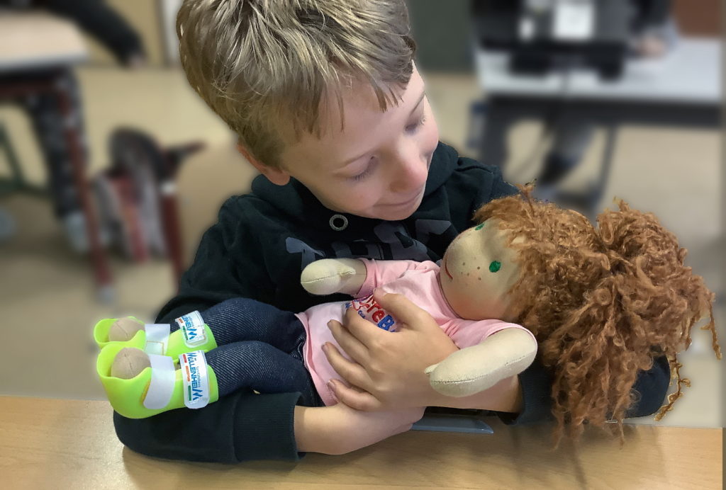 Ein Junge hält eine Handicap Doll in seinem Arm