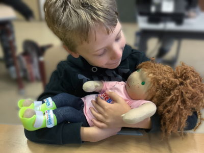 Ein Junge hält eine Handicap Doll in seinem Arm
